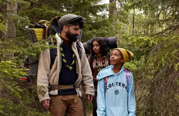 En ledare går med en grupp scouter i skogen. Ledaren lyssnar aktivt på scouten bredvid.